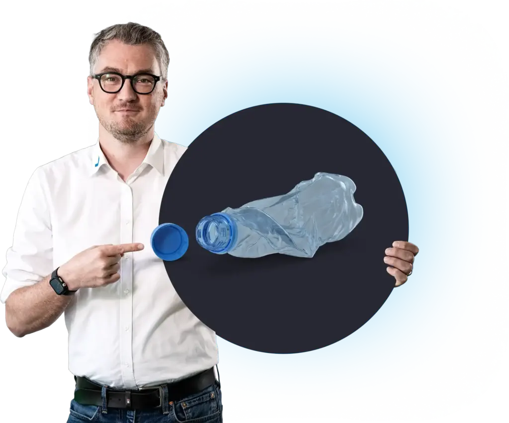 Un uomo indica una bottiglia di plastica accartocciata con il tappo, MODUL6 RZ.
