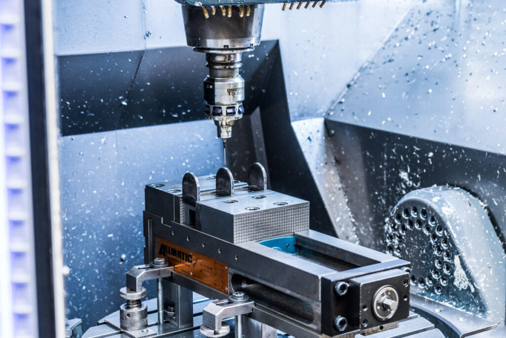 LAVORAZIONE CNC: Una fresatrice lavora un blocco di metallo in officina.