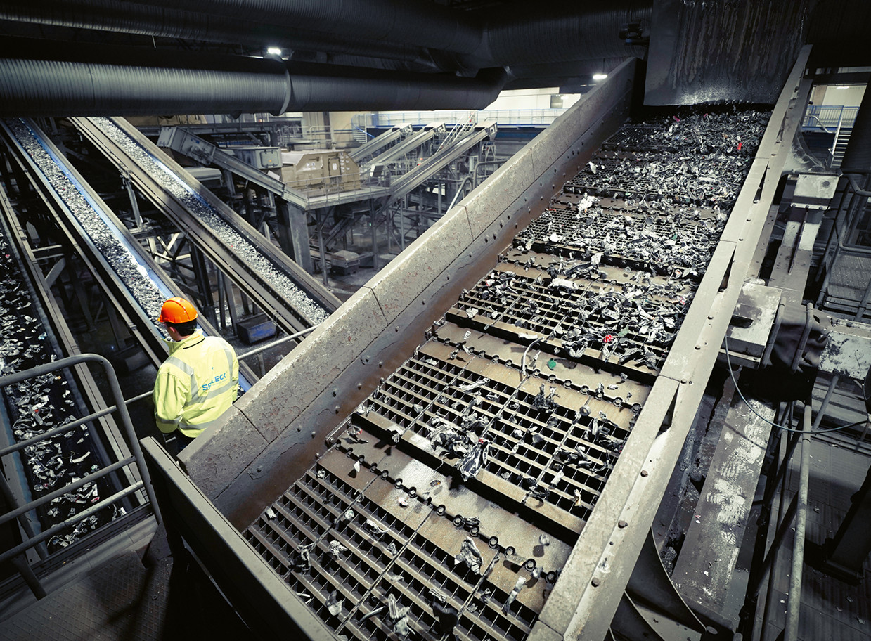 Un operaio controlla il nastro trasportatore in un impianto di riciclaggio.