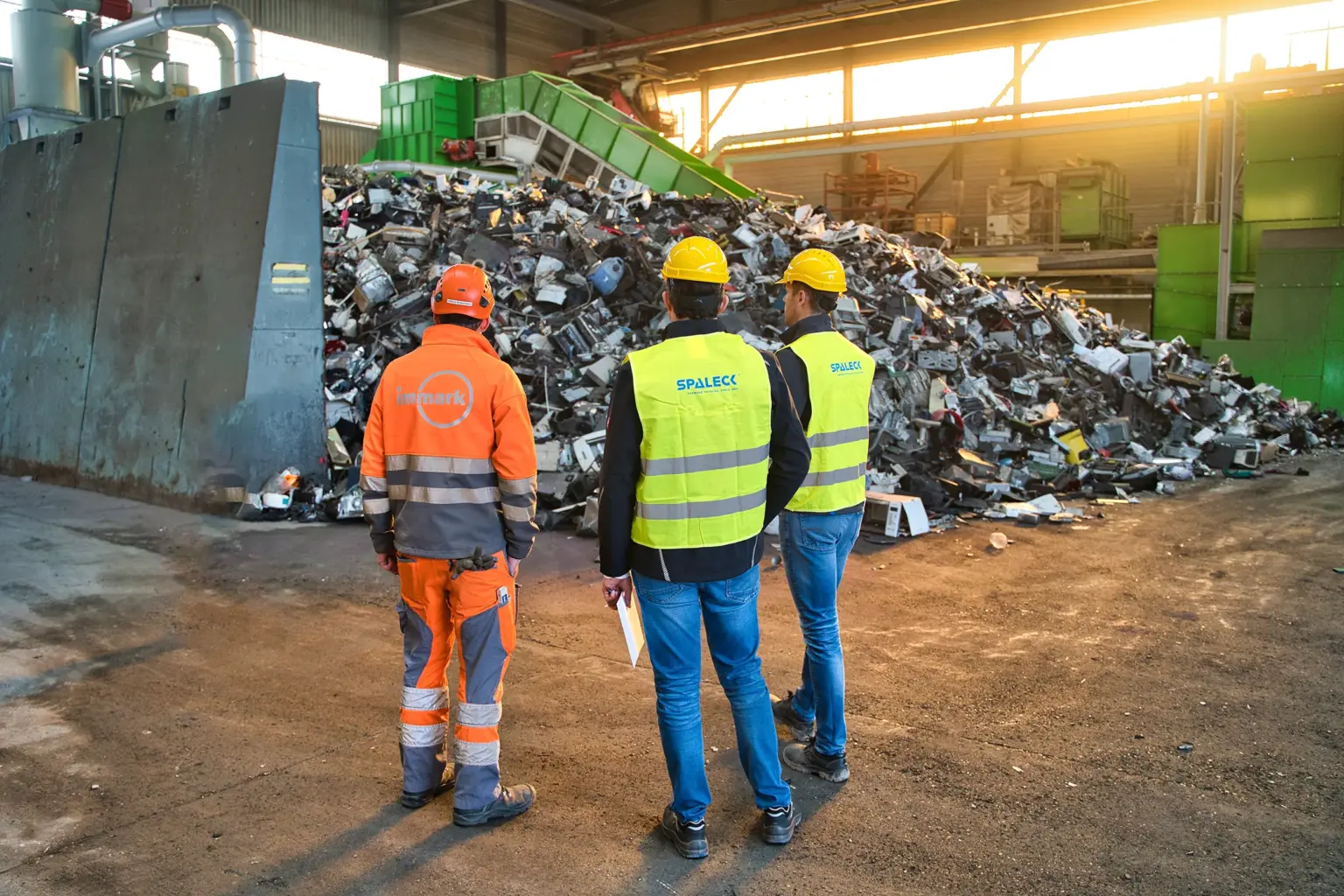 Il responsabile di progetto di Immark e due esperti di vagli di SPALECK si trovano di fronte al materiale di alimentazione non frantumato destinato al nuovo impianto di trattamento dei rifiuti elettrici