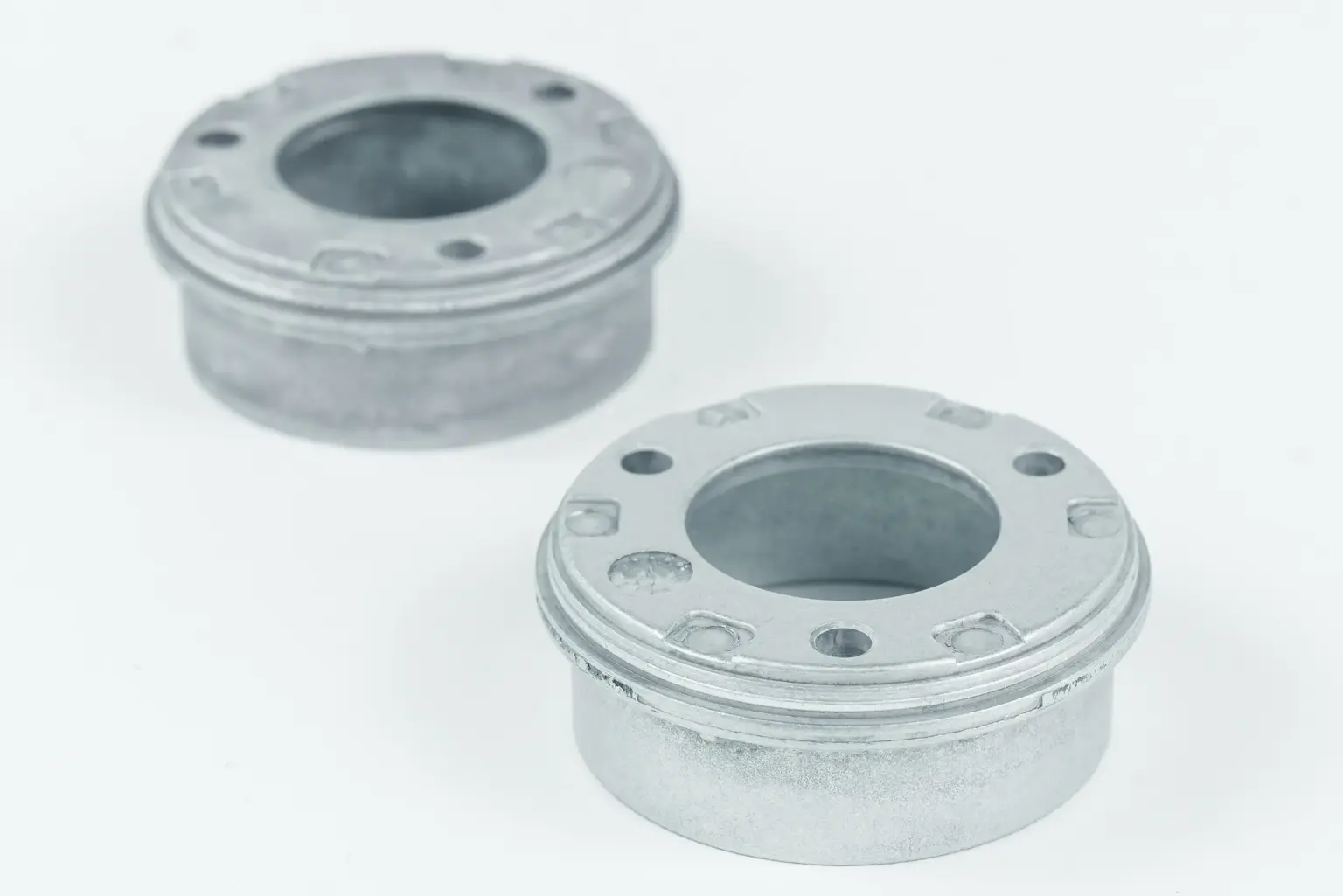 Due componenti metallici con aperture circolari su sfondo chiaro.