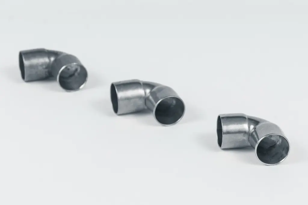 Tre tubi metallici ricurvi su sfondo bianco.