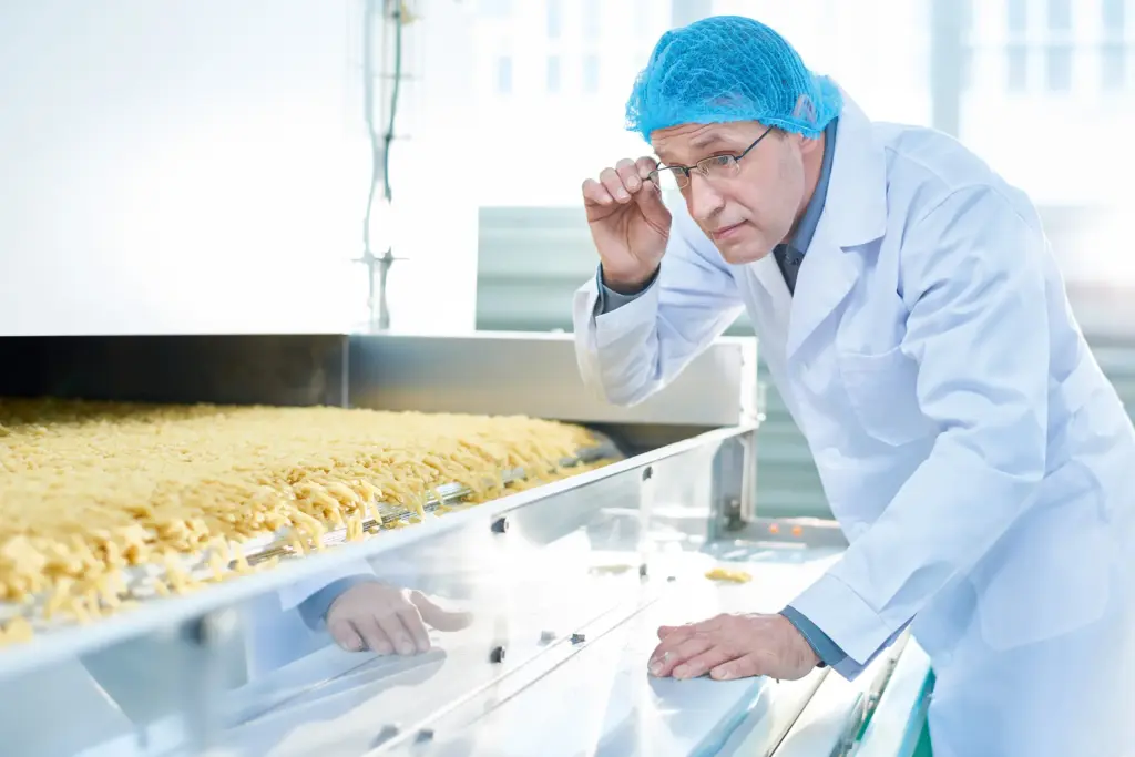 Un uomo in tenuta protettiva ispeziona la produzione alimentare.