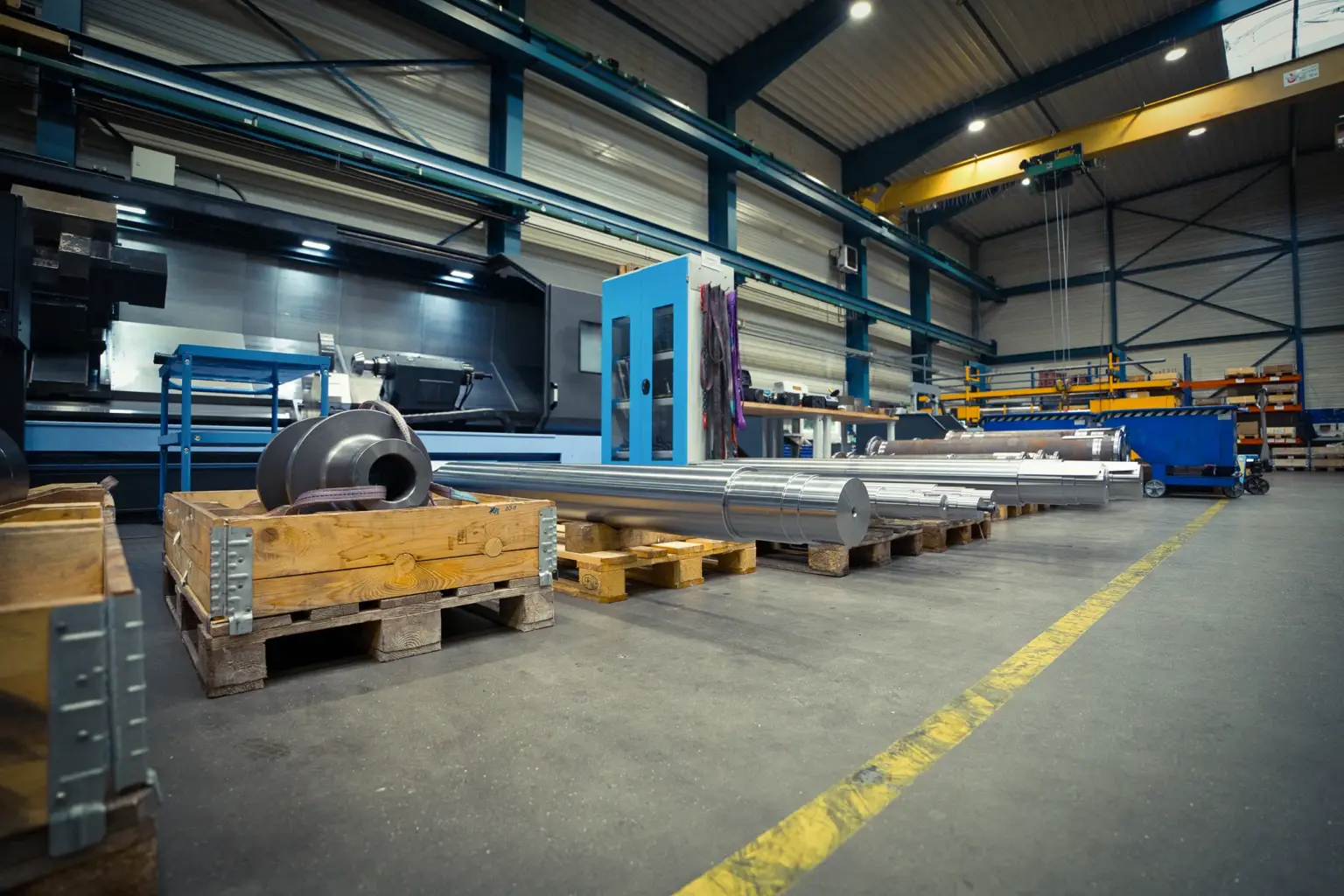 Capannone industriale con pezzi torniti di grandi dimensioni su pallet.
