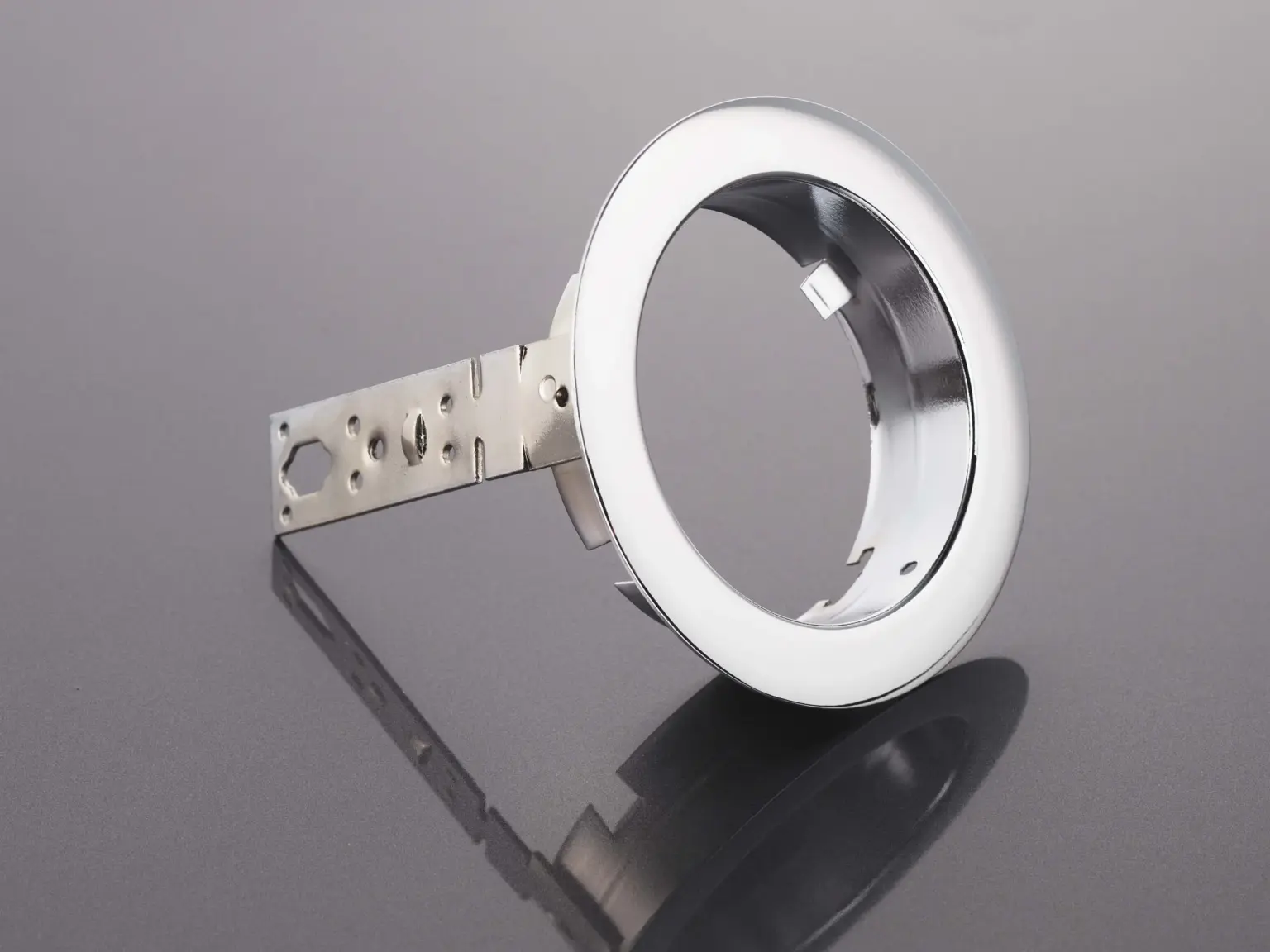 Componente metallico con superficie trattata su fondo riflettente.