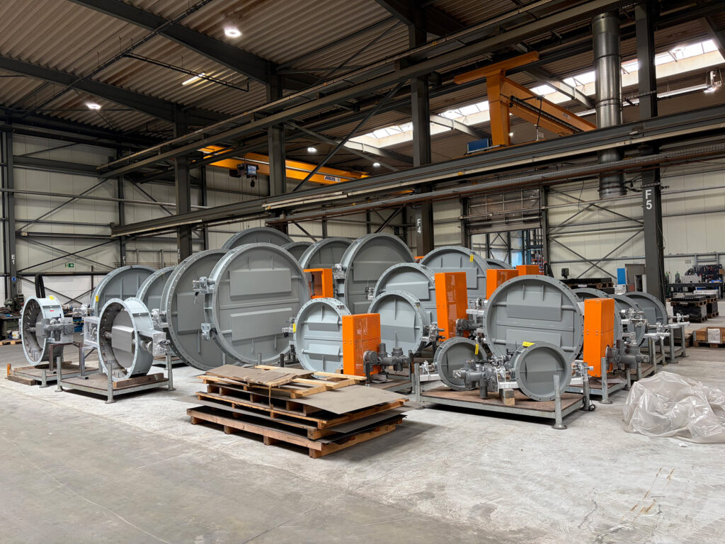 Panoramica di 25 valvole industriali e saracinesche in un capannone di produzione in fase di collaudo per un cementificio
