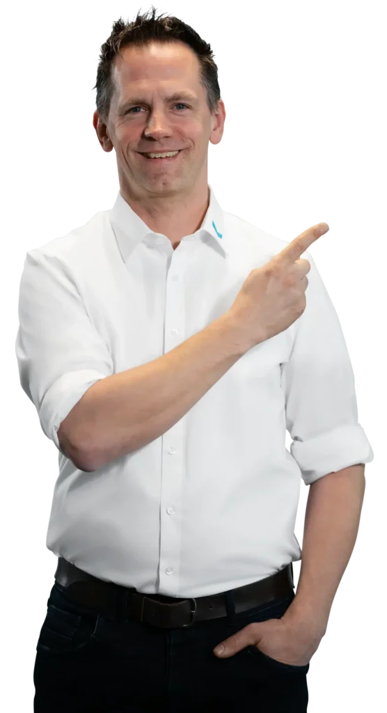 Un uomo in camicia bianca indica sorridendo di lato.