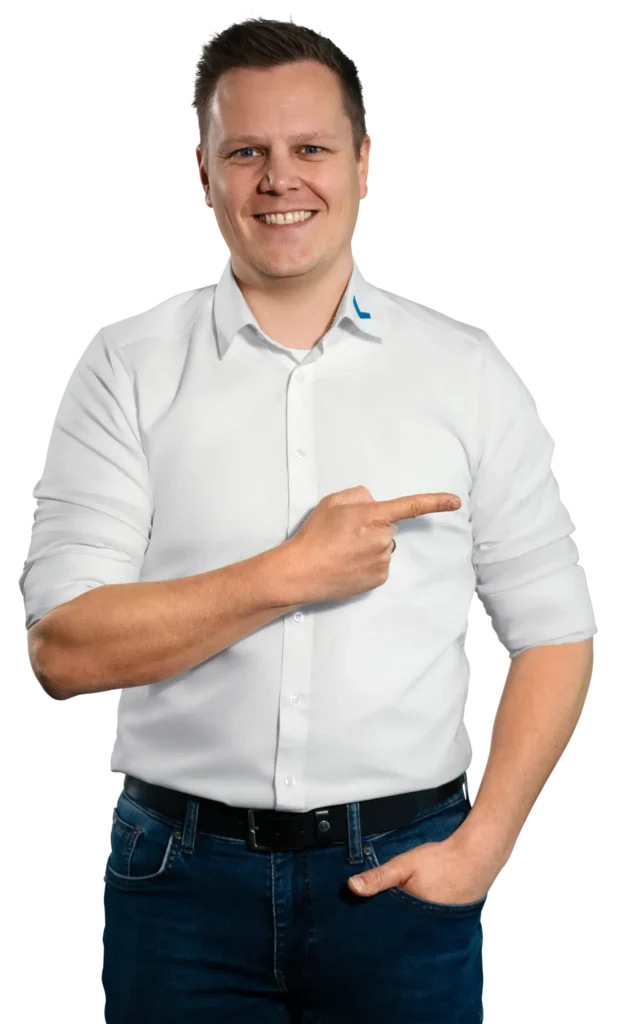 Un uomo in camicia bianca indica sorridendo di lato.