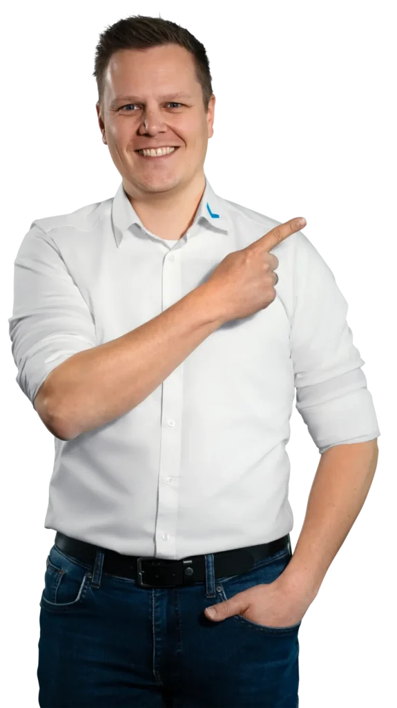 Un uomo con una camicia bianca indica sorridendo verso destra.