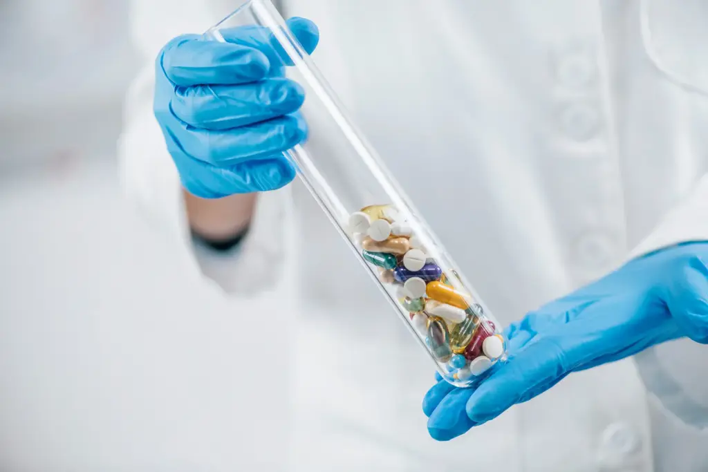 Un dipendente tiene in mano una provetta contenente diverse pillole – immagine simbolica dell’industria farmaceutica